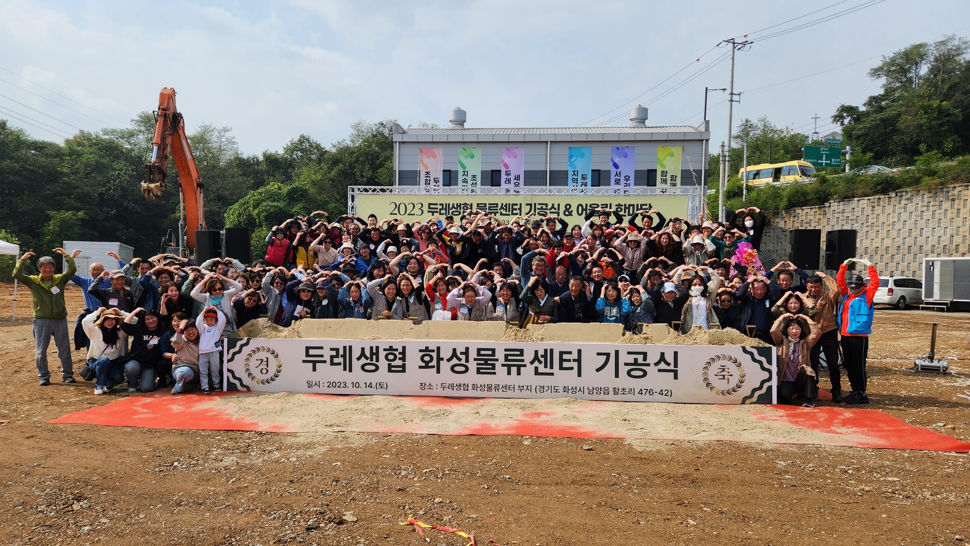 2023 두레생협 화성물류센터 기공식에 모인 조합원과 생산자들이 두 손으로 하트를 그리는 단체사진